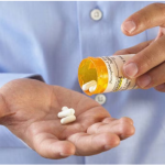 "Person holding a prescription bottle, pouring out pills into their hand, representing the process of tapering off medication."