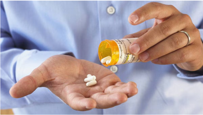 "Person holding a prescription bottle, pouring out pills into their hand, representing the process of tapering off medication."